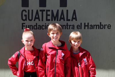 Three children standing in front of a building in Guatemala 