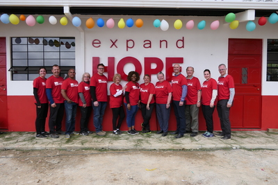 the trip participants standing in front of the expand hope building in a line facing the camera.