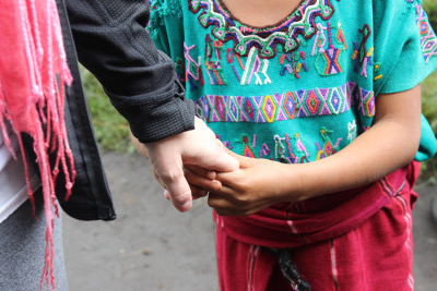 a close up of a girl holding onto an adults hand