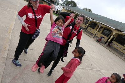 Two expand hope participants in red shirts swinging a little girl between them