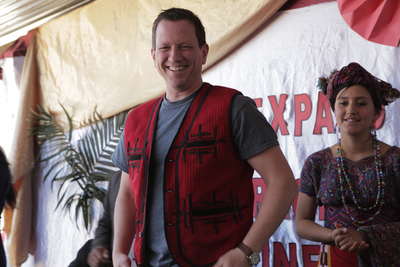a man smiling in a red vest