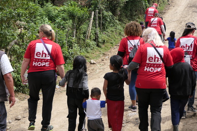 All of the participants of Expand hope walking down a dirt road with children.