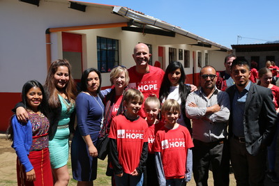 the Schmidt family standing in front of an expand hope building with locals